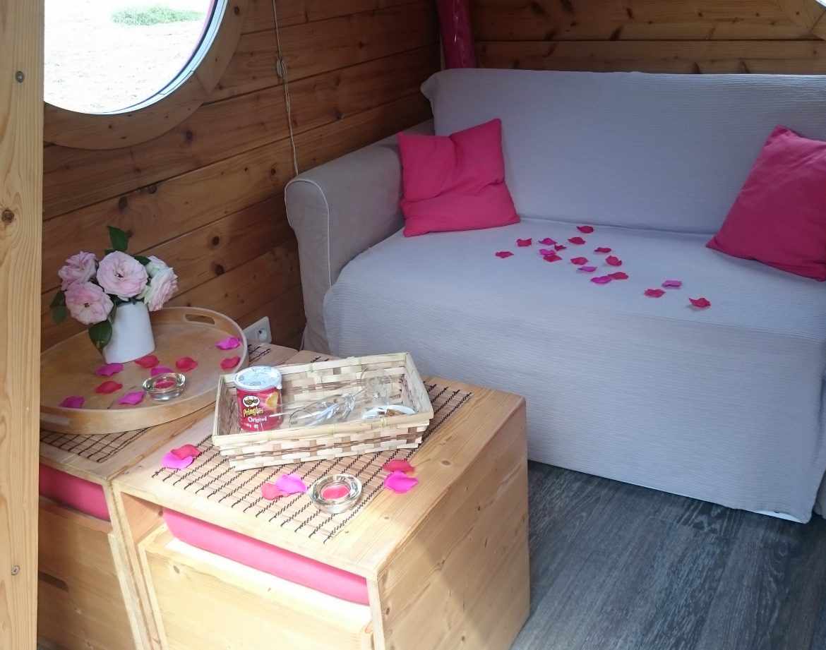 Hébergement insolite en bois avec un canapé, décoré de pétales de rose.