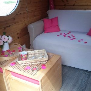 Hébergement insolite en bois avec un canapé, décoré de pétales de rose.
