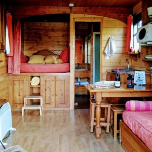 Hébergement insolite : roulotte en bois avec lit douillet et coin repas chaleureux.