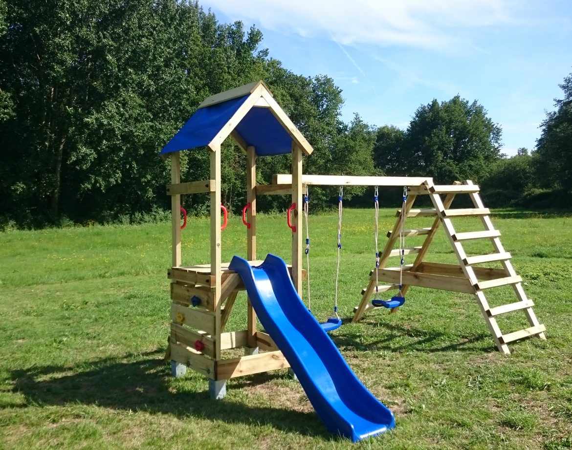 Aire de jeux en bois avec toboggan bleu, idéale pour un hébergement insolite en pleine nature.
