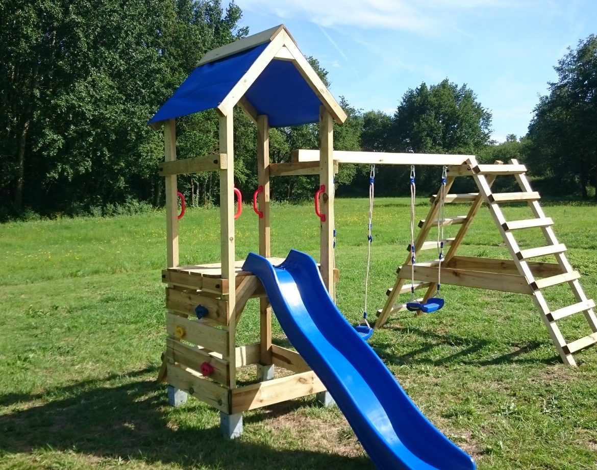 Aire de jeux en bois avec toboggan bleu, idéale pour un hébergement insolite en pleine nature.