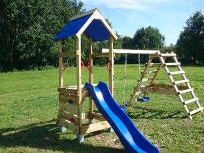 Aire de jeux en bois avec toboggan bleu, idéale pour un hébergement insolite en pleine nature.