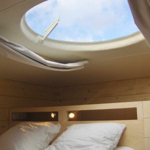 Hébergement insolite en cabane avec un puits de lumière offrant une vue sur le ciel.