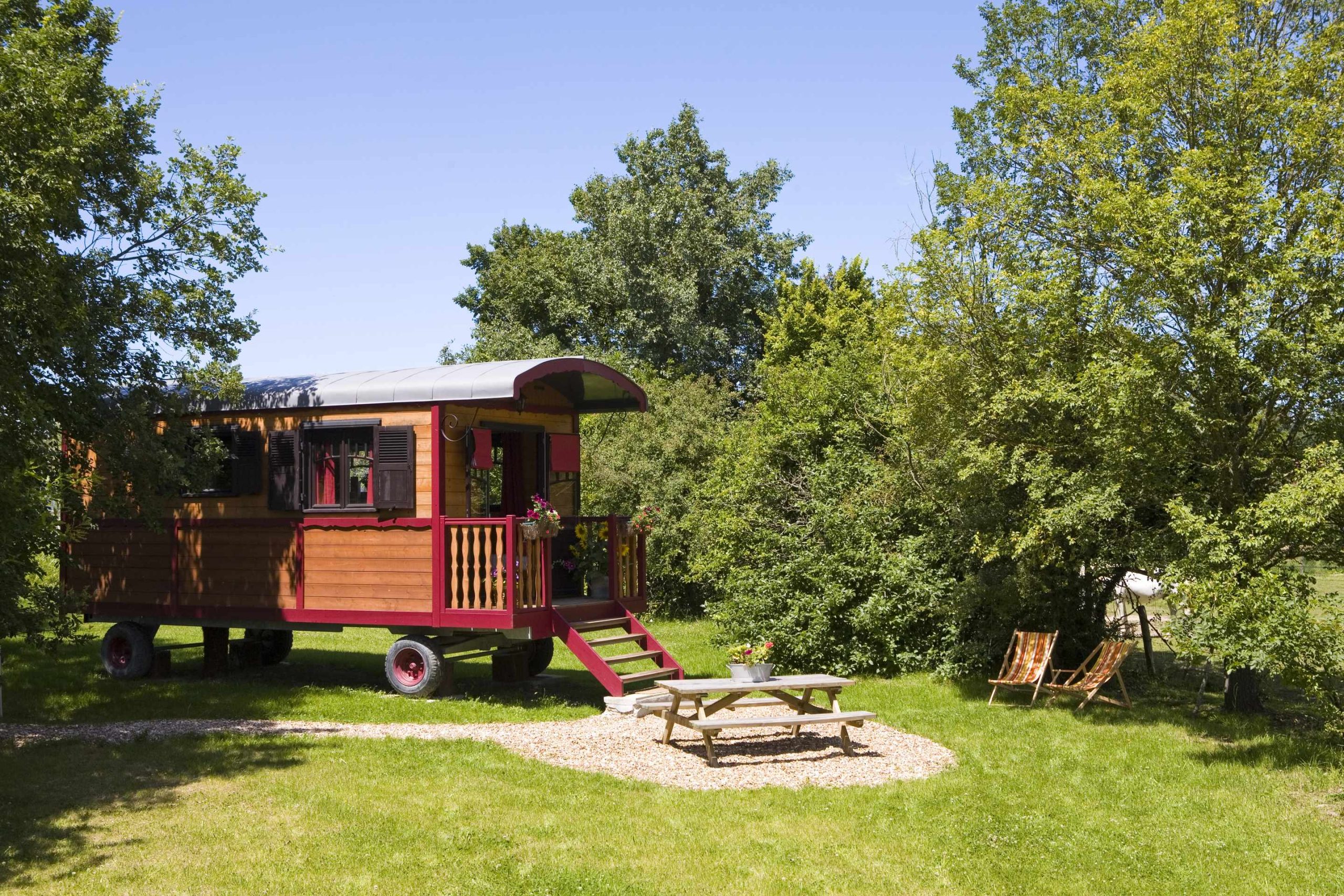 _MG_9437 Charmante roulotte colorée entourée de verdure, avec un coin repas extérieur.