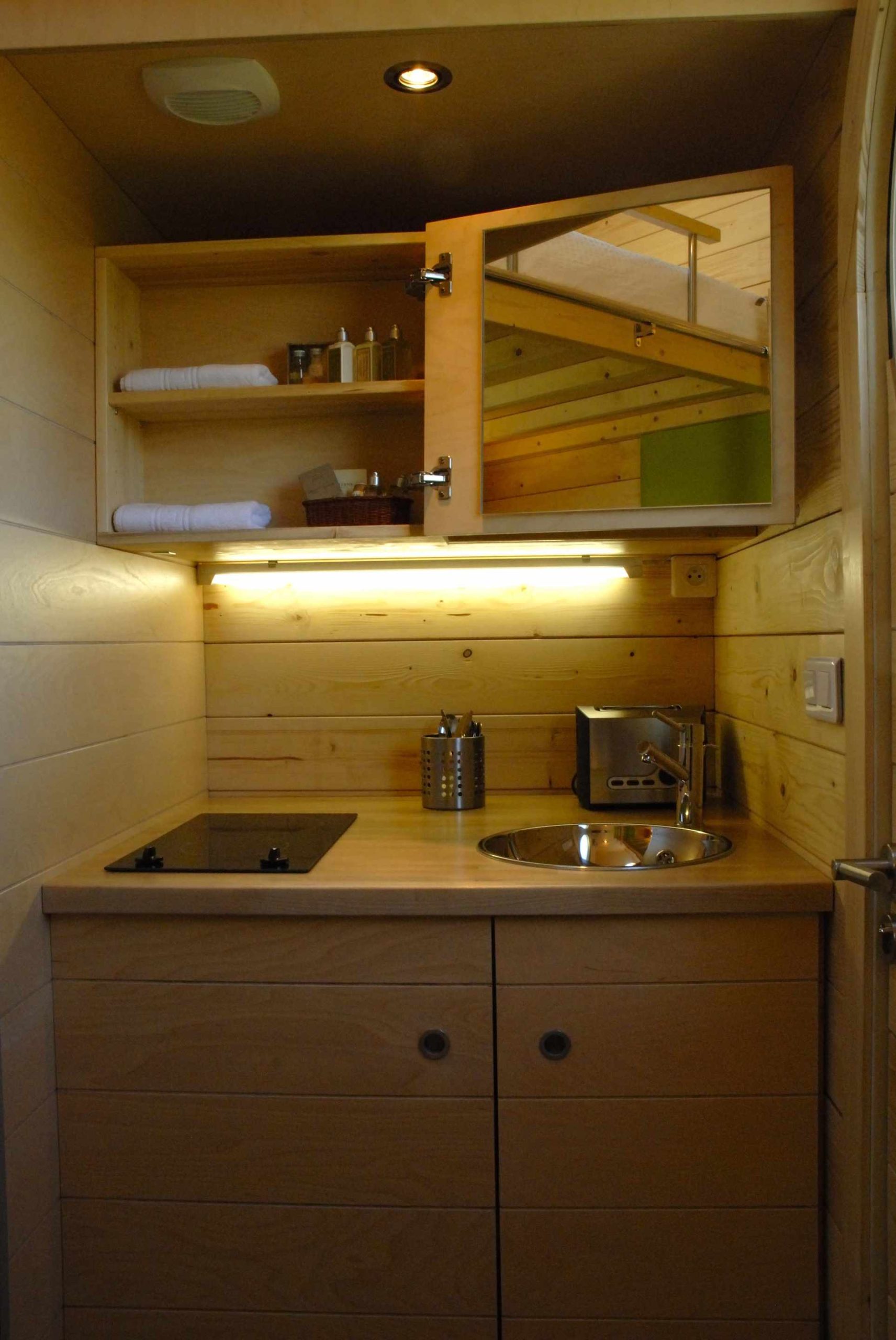 carre 4 Hébergement insolite en bois avec kitchenette moderne et éclairage chaleureux.