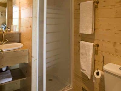 Salle de bain en bois dans un hébergement insolite, avec douche et lavabo élégant.