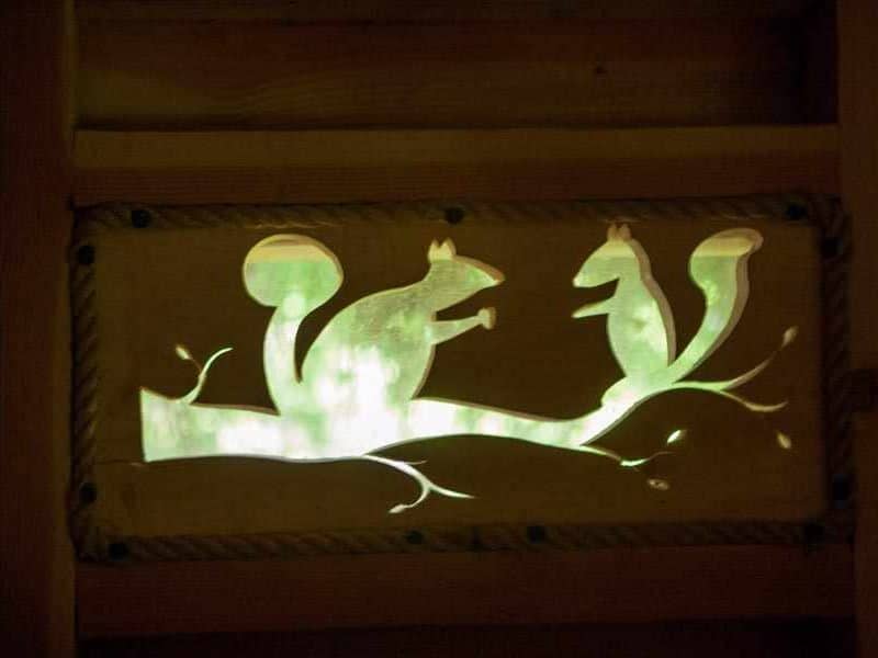 Cabane en bois avec une décoration lumineuse de écureuils sur une branche.