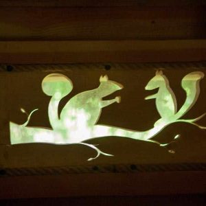 Cabane en bois avec une décoration lumineuse de écureuils sur une branche.