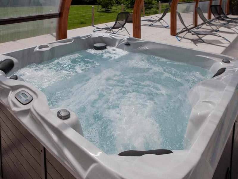 Jacuzzi relaxant dans un hébergement de luxe, entouré de chaises longues.