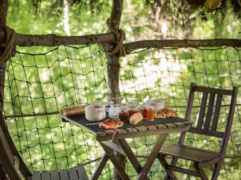 Cabane dans les arbres avec une table accueillante et un petit-déjeuner appétissant.