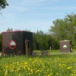 Hébergement insolite en cabanes rondes, entourées de fleurs sauvages et verdure.