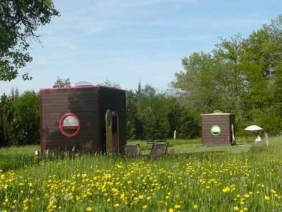 Hébergement insolite en cabanes rondes, entourées de fleurs sauvages et verdure.