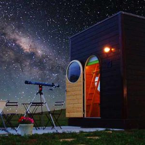 Hébergement insolite en cabane, sous un ciel étoilé avec télescope et chaises.