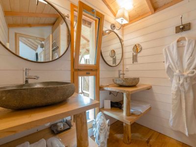 Salle de bain dun hébergement insolite en Aquitaine, avec vasque en pierre et lumière naturelle.