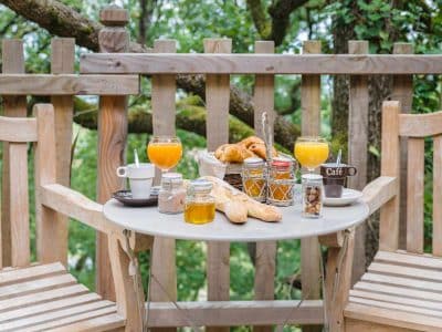 Hébergement insolite en Aquitaine : petit-déjeuner sur une terrasse en bois dans les arbres.