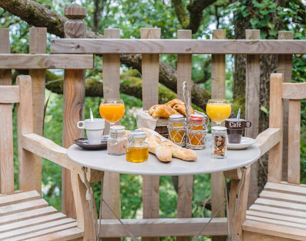 Hébergement insolite en Aquitaine : petit-déjeuner sur une terrasse en bois dans les arbres.