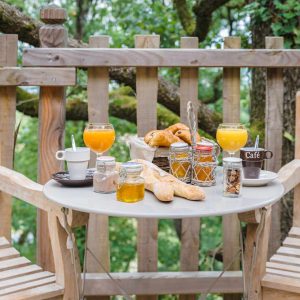 Hébergement insolite en Aquitaine : petit-déjeuner sur une terrasse en bois dans les arbres.
