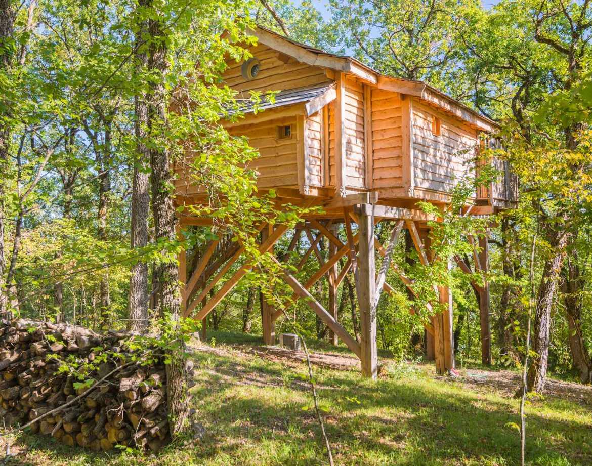 Cabane perchée en bois, entourée darbres verdoyants en Aquitaine.