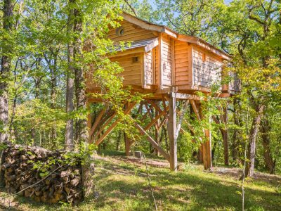 Cabane perchée en bois, entourée darbres verdoyants en Aquitaine.
