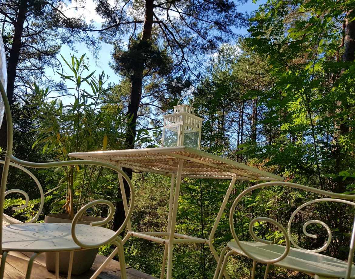 Hébergement insolite en cabane, avec une terrasse et vue sur la forêt verdoyante.