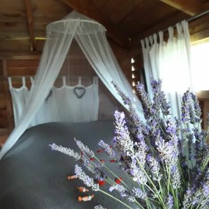 Cabane en bois cosy avec lit à baldaquin et bouquet de lavande.