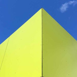 Cabane moderne et colorée, au design audacieux, sous un ciel bleu éclatant.