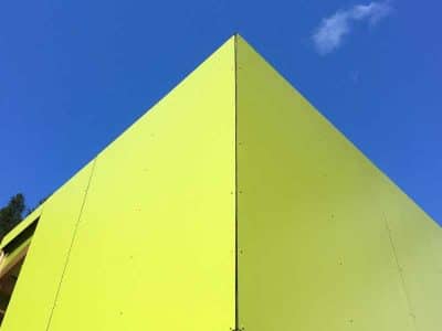 Cabane moderne et colorée, au design audacieux, sous un ciel bleu éclatant.