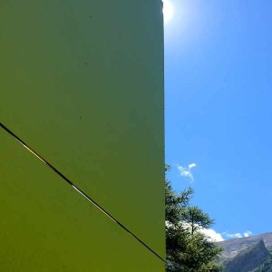 Hébergement insolite en forme géométrique, entouré de montagnes sous un ciel bleu.