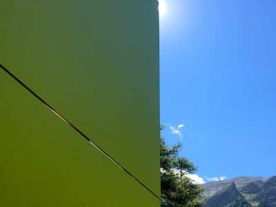 Hébergement insolite en forme géométrique, entouré de montagnes sous un ciel bleu.