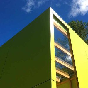 Cabane moderne en bois vert, offrant une vue dégagée sur le ciel azur.