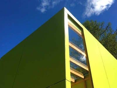 Cabane moderne en bois vert, offrant une vue dégagée sur le ciel azur.