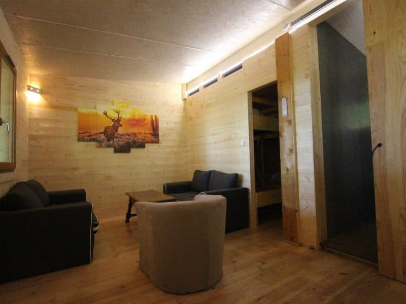 Chalet en bois avec un salon lumineux et un tableau de cerf sur le mur.