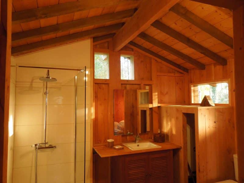 Cabane en bois avec un intérieur lumineux et des poutres apparentes.