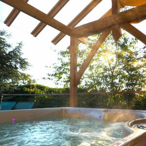 Hébergement insolite en Auvergne-Rhône-Alpes avec jacuzzi sous une structure en bois.