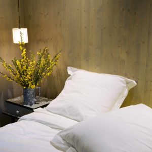 Chambre cosy en hébergement insolite à Limousin, avec fleurs jaunes sur table de nuit.