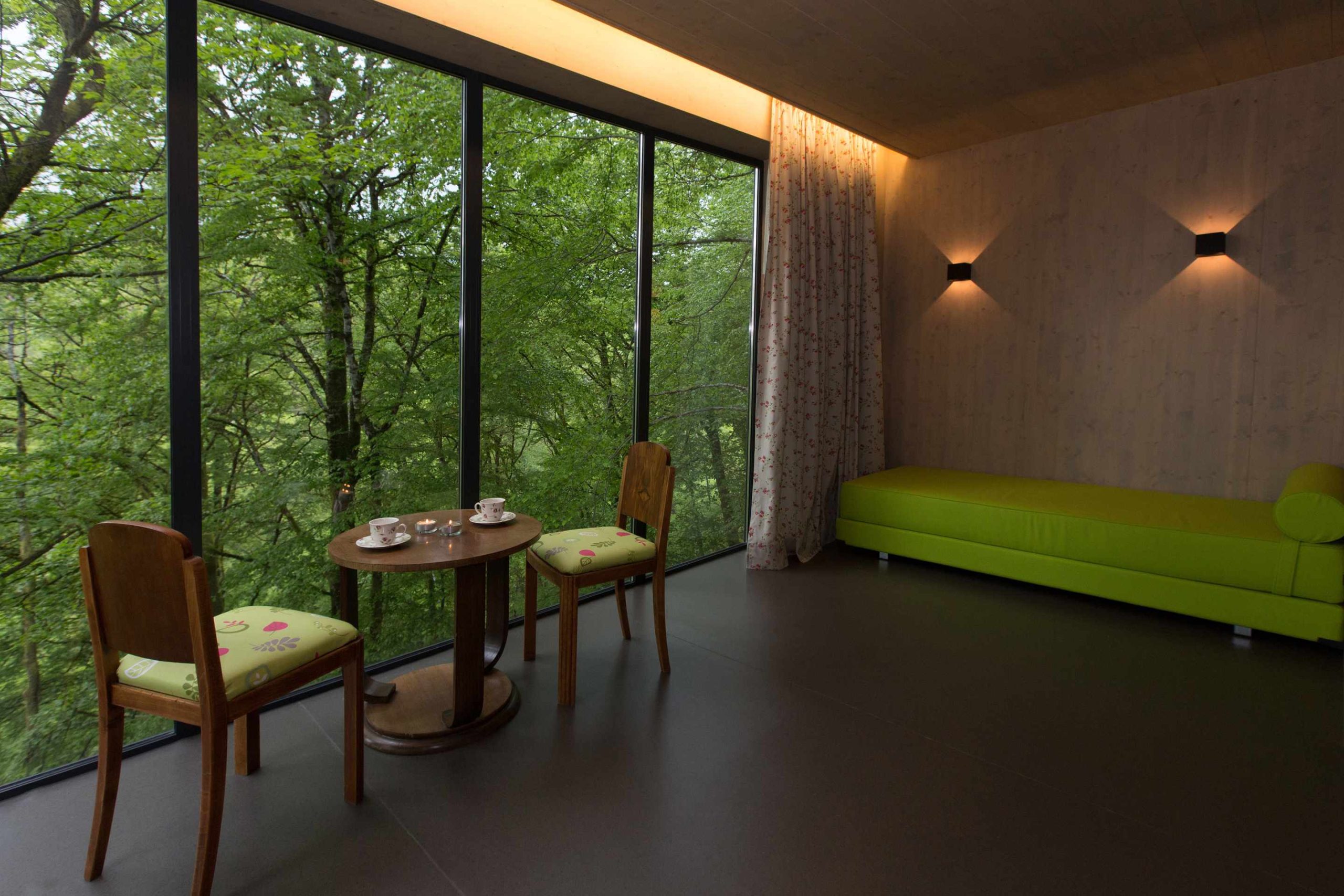 E98A8030 Hébergement insolite à Limousin : intérieur moderne avec vue sur la forêt et mobilier coloré.