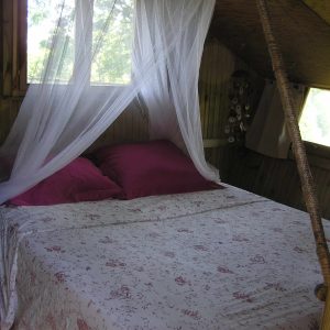 Cabane perchée en Bretagne avec un lit douillet et des draps fleuris.