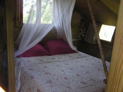 Cabane perchée en Bretagne avec un lit douillet et des draps fleuris.