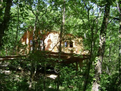 Cabane perchée en bois, entourée darbres verdoyants en Midi-Pyrénées.