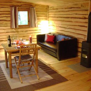 Cabane en bois à Midi-Pyrénées, avec un salon cosy et une table en bois.