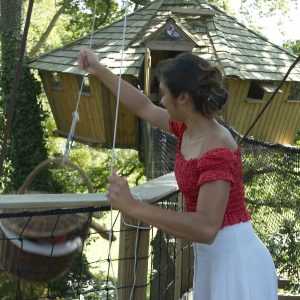 Cabane perchée en Bretagne, avec un toit en ardoise et un accès par une passerelle.