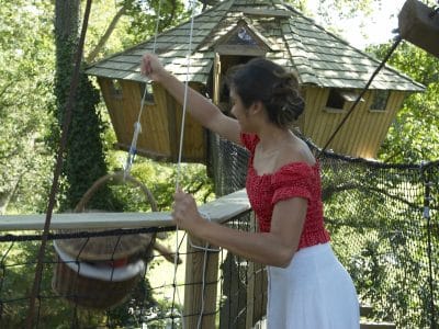 Cabane perchée en Bretagne, avec un toit en ardoise et un accès par une passerelle.