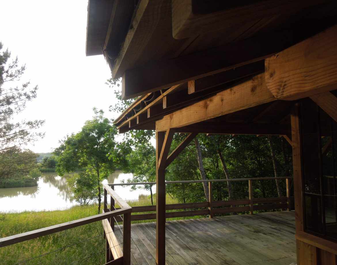 Cabane en bois sur pilotis avec vue sur un lac paisible en Aquitaine.