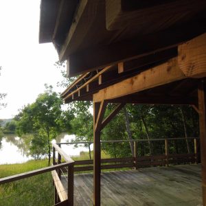 Cabane en bois sur pilotis avec vue sur un lac paisible en Aquitaine.