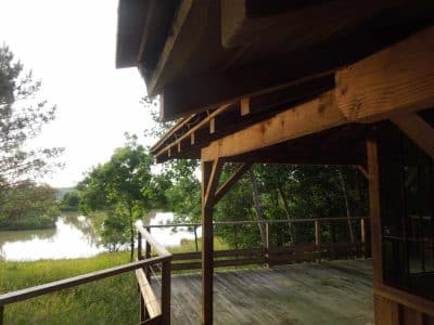 Cabane en bois sur pilotis avec vue sur un lac paisible en Aquitaine.
