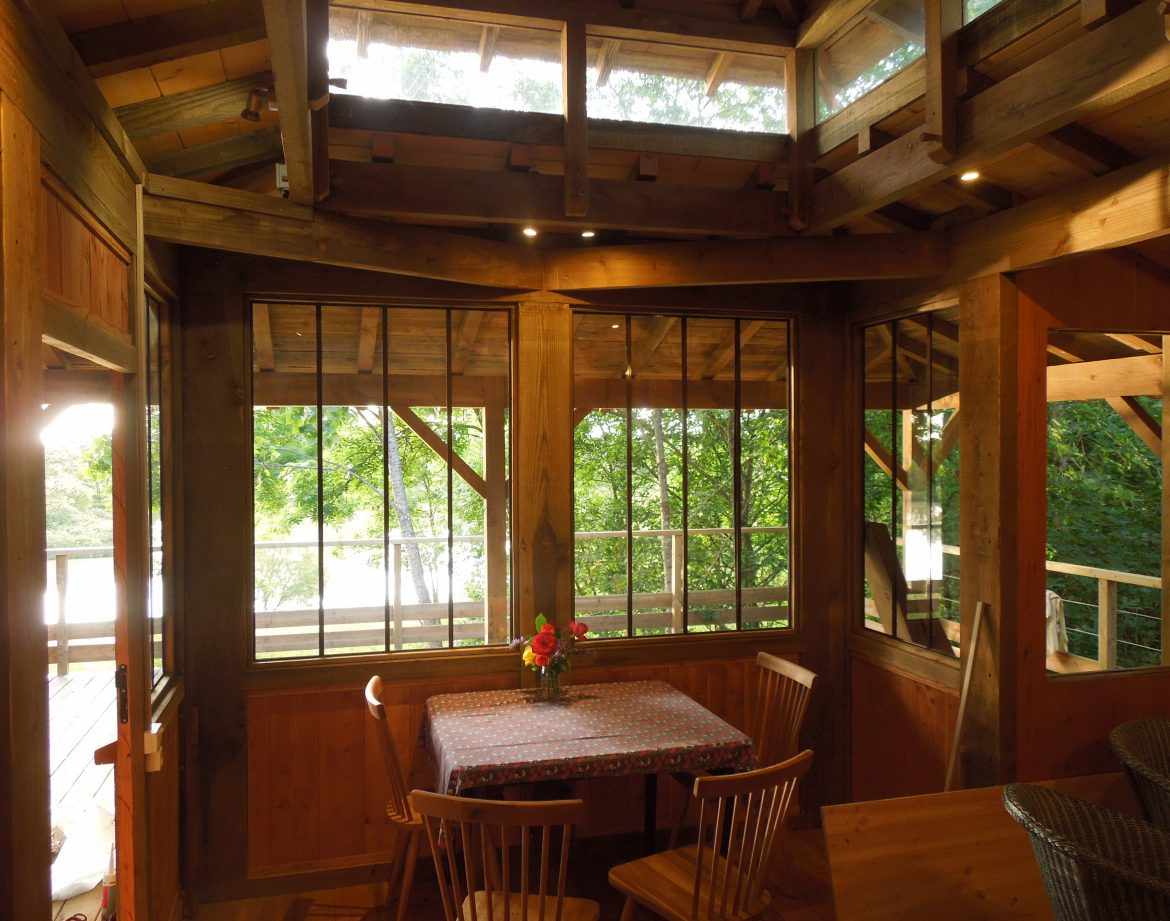 Cabane en bois avec grandes fenêtres, vue sur la nature, ambiance chaleureuse.