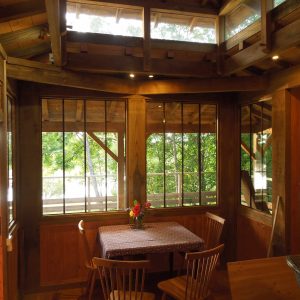 Cabane en bois avec grandes fenêtres, vue sur la nature, ambiance chaleureuse.
