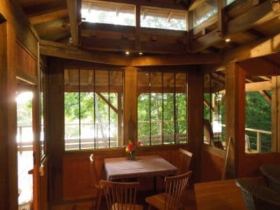 Cabane en bois avec grandes fenêtres, vue sur la nature, ambiance chaleureuse.
