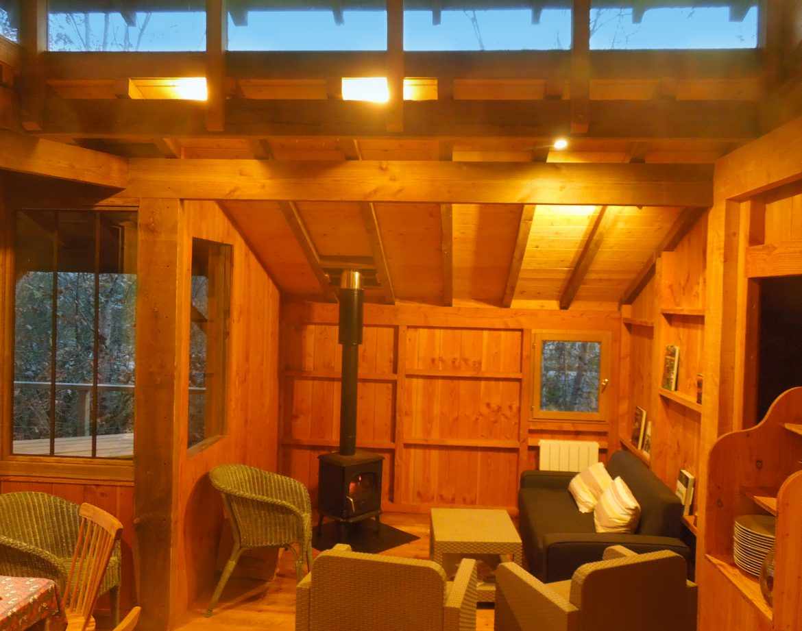 Cabane en bois chaleureuse en Aquitaine, avec poêle à bois et vue sur la nature.