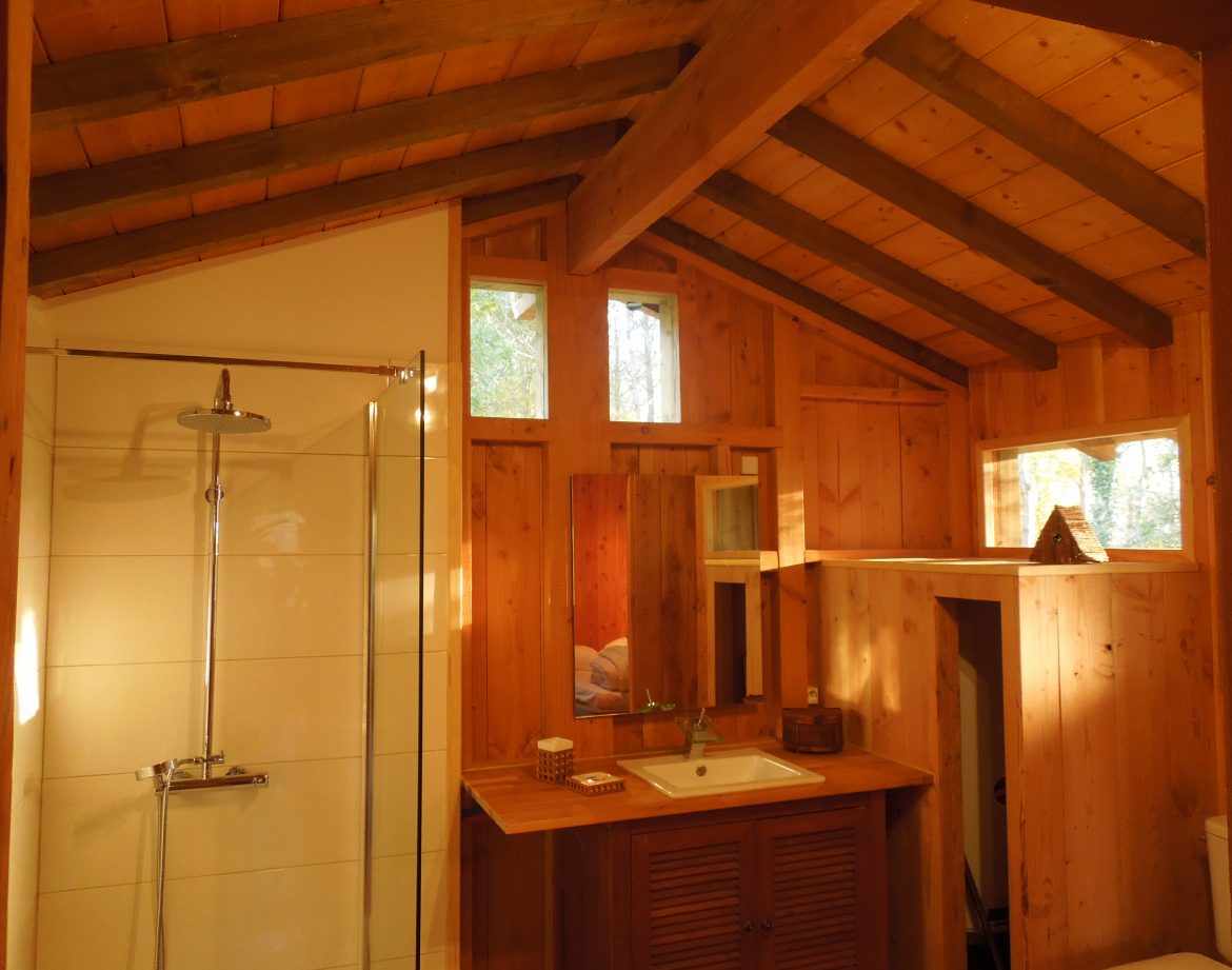 Cabane en bois avec un intérieur lumineux et des fenêtres en hauteur.